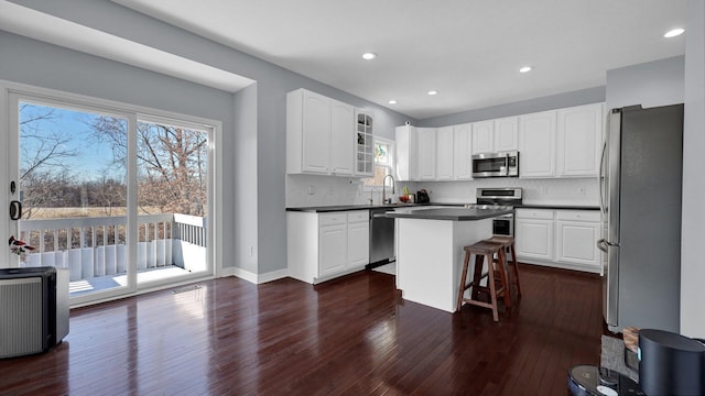 kitchen featuring a breakfast bar area, stainless steel appliances, dark hardwood / wood-style floors, white cabinets, and a kitchen island