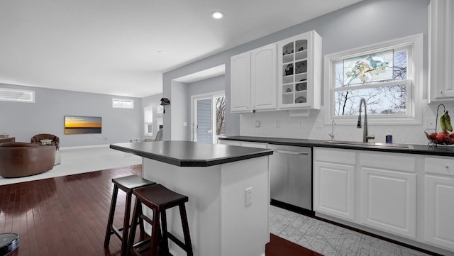 kitchen with dishwasher, white cabinetry, sink, a kitchen breakfast bar, and decorative backsplash