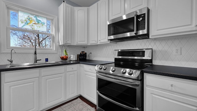 kitchen featuring sink, backsplash, white cabinets, and appliances with stainless steel finishes