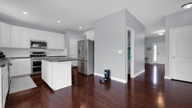 kitchen featuring dark wood-type flooring, white cabinetry, a kitchen breakfast bar, stainless steel appliances, and a center island