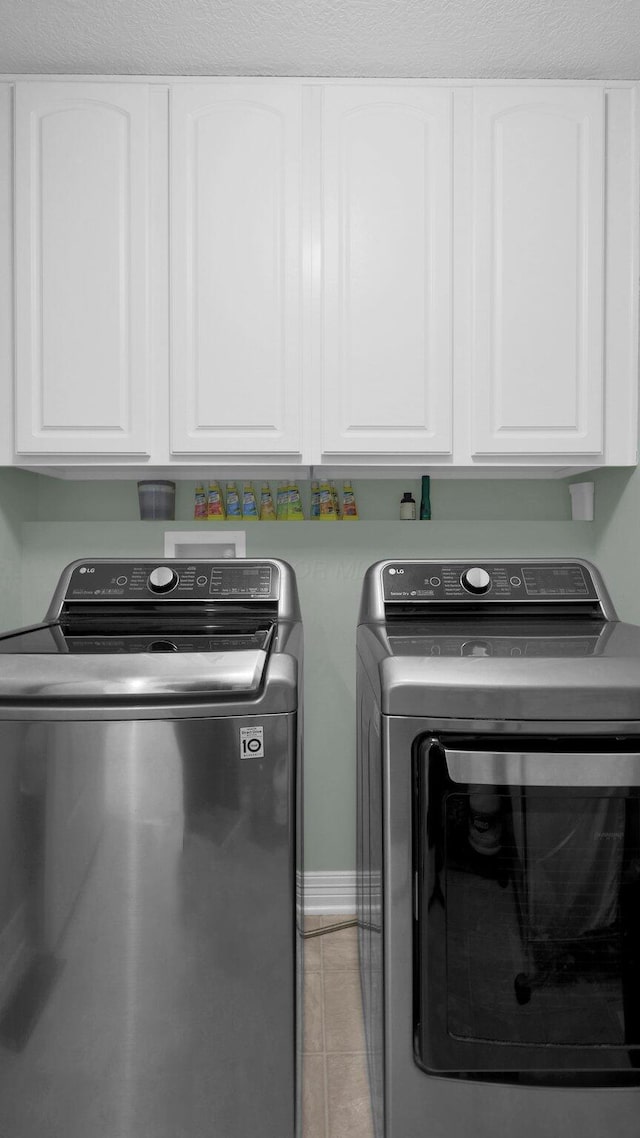 laundry room featuring cabinets, independent washer and dryer, and light tile patterned floors