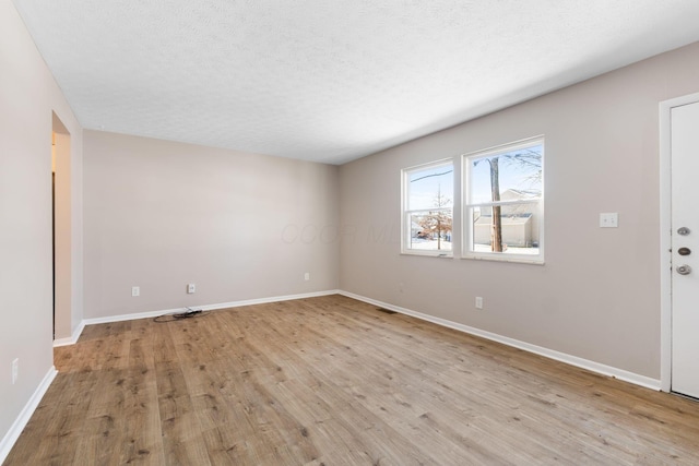 spare room featuring a textured ceiling and light wood-type flooring