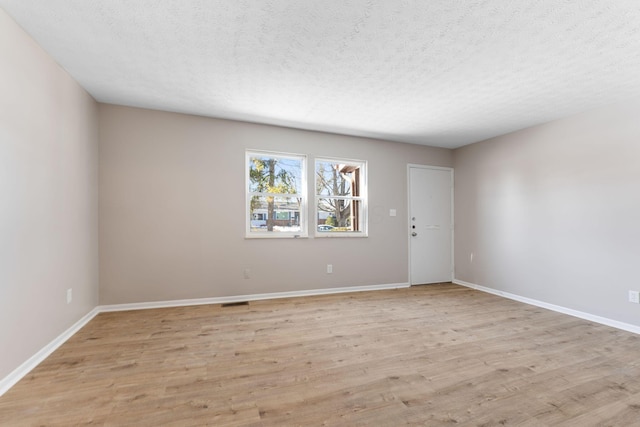 unfurnished room featuring light hardwood / wood-style floors and a textured ceiling