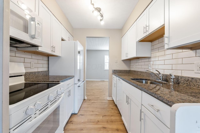 kitchen featuring white cabinetry, sink, white appliances, and dark stone counters