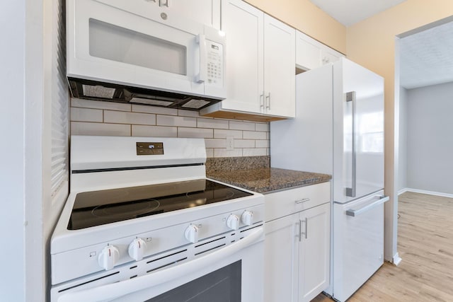 kitchen with white cabinetry, white appliances, dark stone counters, and tasteful backsplash