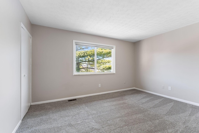 carpeted spare room featuring a textured ceiling