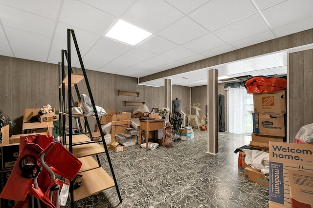 basement featuring a paneled ceiling and wooden walls