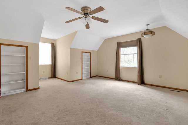 additional living space featuring ceiling fan, light colored carpet, lofted ceiling, and built in shelves