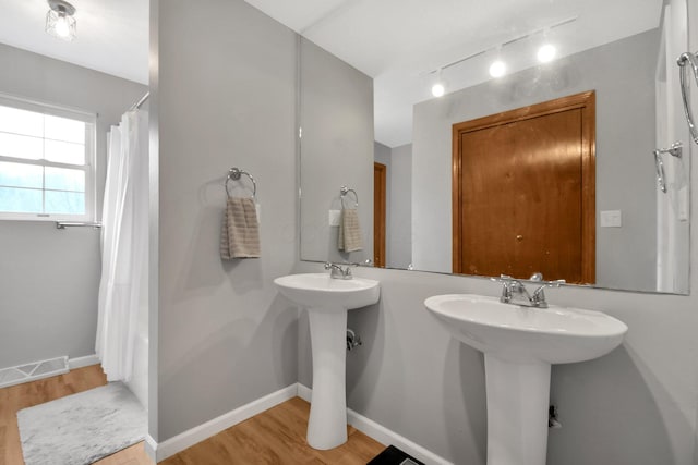 bathroom with track lighting, wood-type flooring, and shower / tub combo