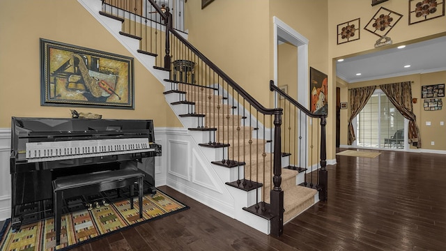 staircase featuring crown molding, hardwood / wood-style floors, and a high ceiling