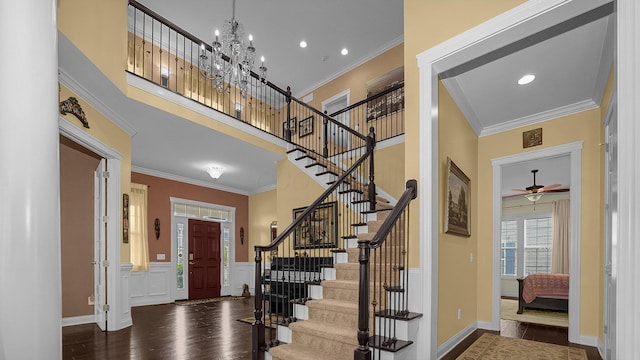 foyer with dark hardwood / wood-style flooring, a notable chandelier, crown molding, and a towering ceiling