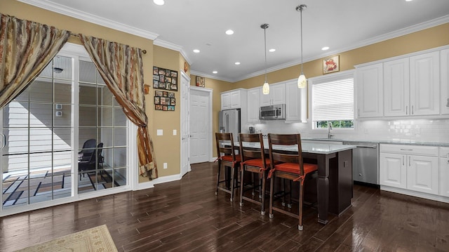 kitchen with a breakfast bar, stainless steel appliances, a center island, light stone counters, and decorative light fixtures