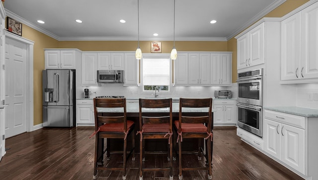 kitchen with light stone counters, pendant lighting, stainless steel appliances, and white cabinets