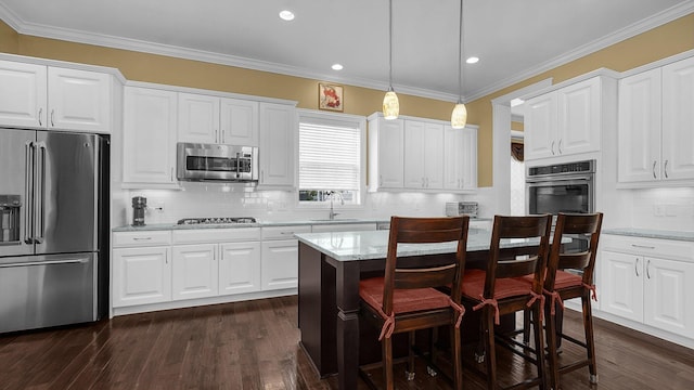 kitchen with appliances with stainless steel finishes, sink, white cabinets, hanging light fixtures, and light stone countertops