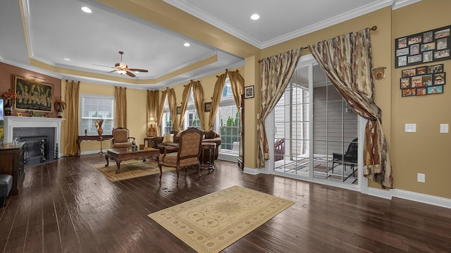 living room with hardwood / wood-style flooring, ceiling fan, a tray ceiling, and crown molding