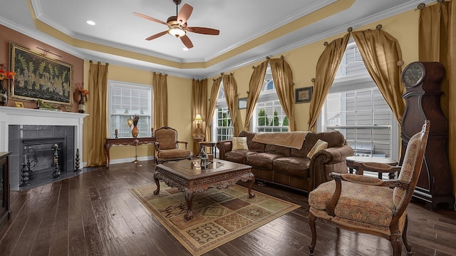 sitting room with ornamental molding, dark hardwood / wood-style floors, a tray ceiling, ceiling fan, and a fireplace