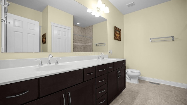 bathroom with tile patterned flooring, vanity, a tile shower, and toilet