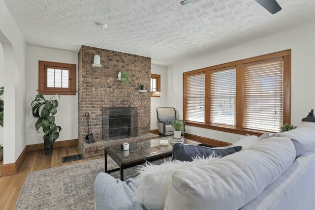 living room featuring a fireplace, light hardwood / wood-style floors, and a textured ceiling