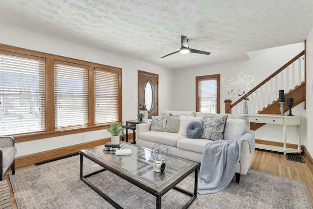 living room with ceiling fan, a healthy amount of sunlight, a textured ceiling, and light hardwood / wood-style flooring