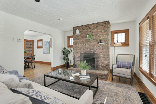 living room featuring a brick fireplace, hardwood / wood-style floors, and a textured ceiling