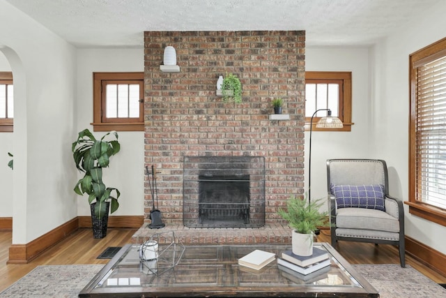 living room featuring light hardwood / wood-style flooring, a fireplace, plenty of natural light, and a textured ceiling