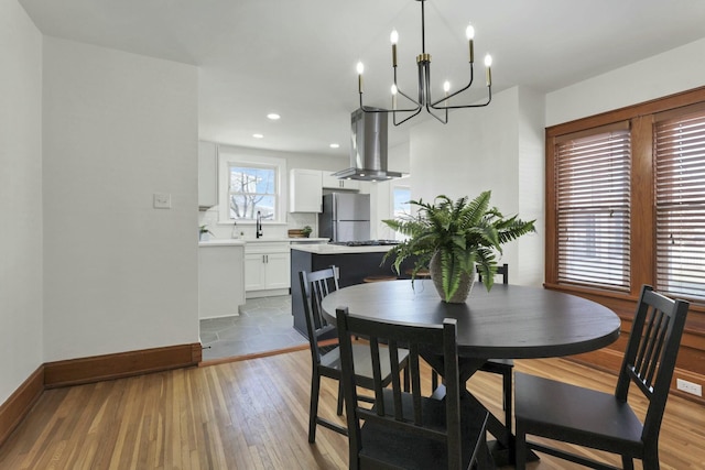 dining room featuring a notable chandelier, sink, and light wood-type flooring