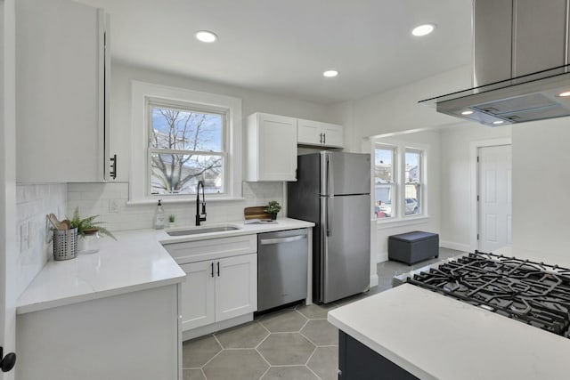 kitchen with sink, backsplash, stainless steel appliances, island range hood, and white cabinets