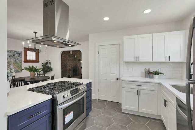 kitchen featuring blue cabinets, white cabinets, decorative backsplash, island exhaust hood, and stainless steel appliances