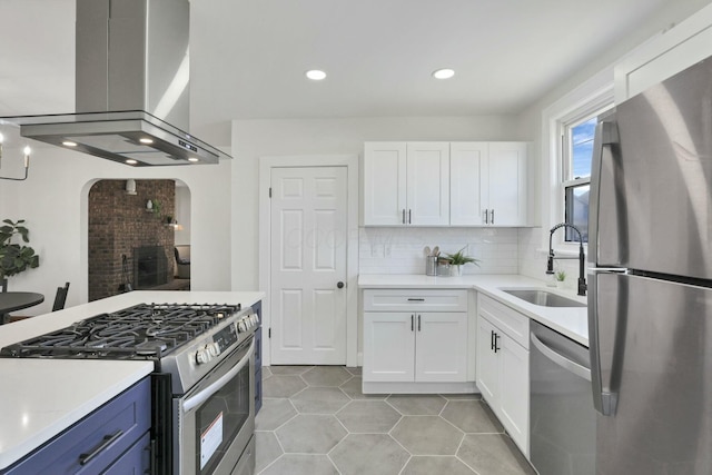 kitchen with sink, backsplash, stainless steel appliances, island range hood, and white cabinets