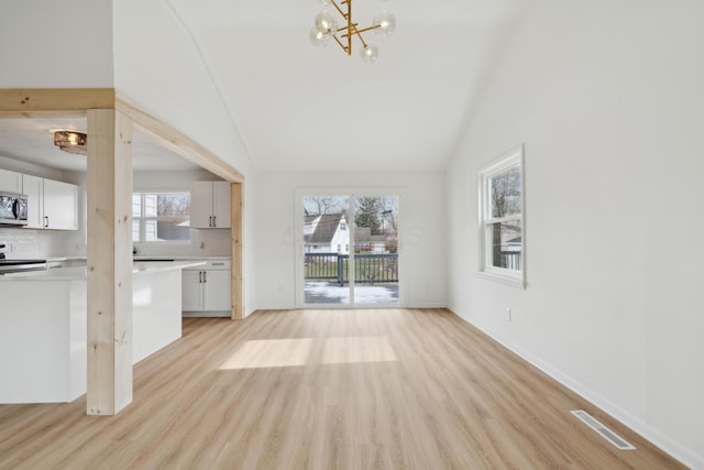 unfurnished living room with vaulted ceiling, a chandelier, and light wood-type flooring