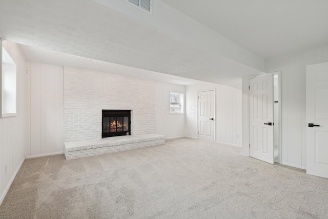 unfurnished living room with light colored carpet and a brick fireplace