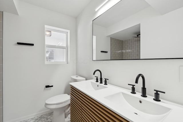 bathroom with vanity, a tile shower, and toilet