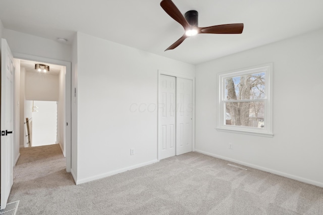 unfurnished bedroom featuring light colored carpet, a closet, and ceiling fan