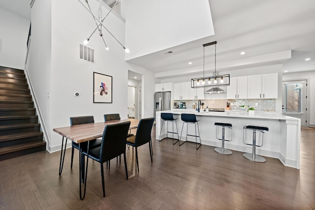 dining area featuring sink, dark hardwood / wood-style floors, and a high ceiling