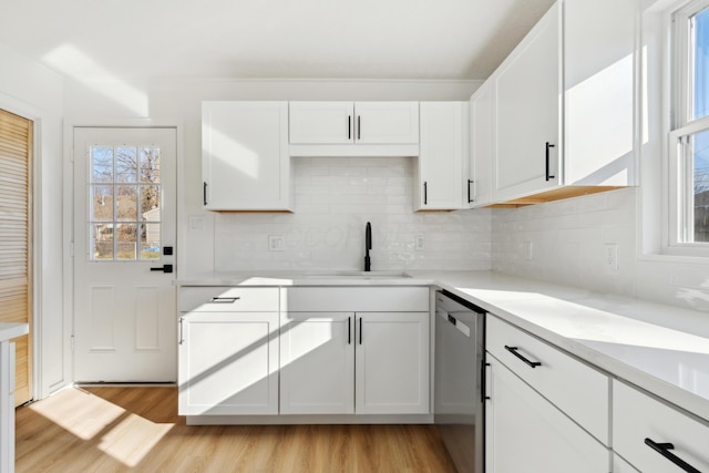 kitchen featuring sink, stainless steel dishwasher, white cabinets, and light wood-type flooring