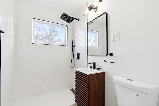 bathroom with vanity, tiled shower, and toilet