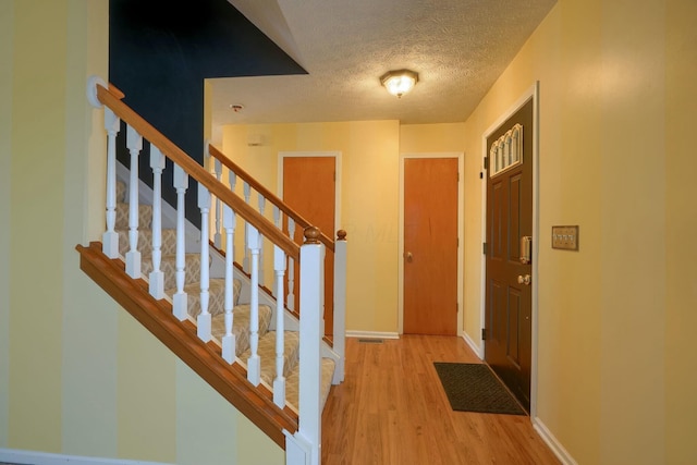 foyer with a textured ceiling and light wood-type flooring