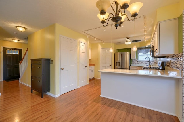 kitchen with stainless steel fridge, light hardwood / wood-style floors, white cabinets, decorative backsplash, and kitchen peninsula