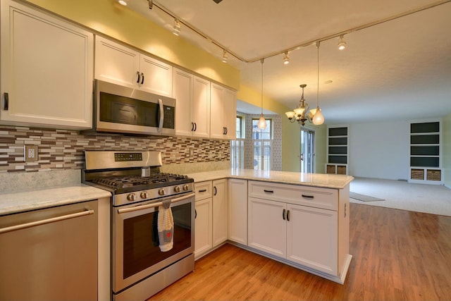 kitchen featuring stainless steel appliances, hanging light fixtures, light hardwood / wood-style flooring, and kitchen peninsula