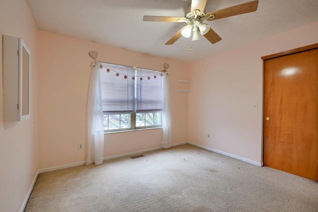 carpeted spare room featuring ceiling fan and a textured ceiling