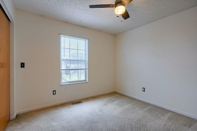 carpeted empty room featuring ceiling fan and a textured ceiling