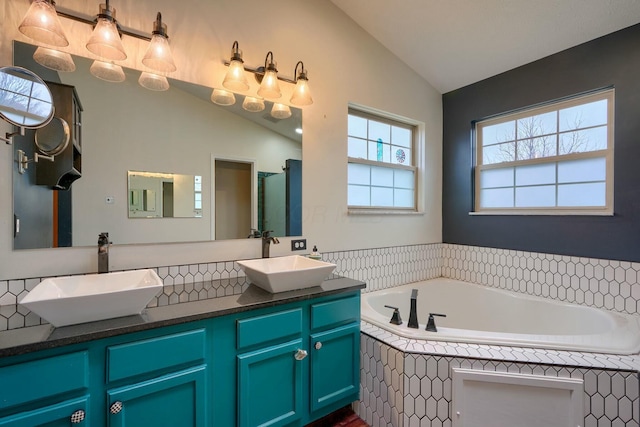 bathroom with vanity, lofted ceiling, and tiled bath