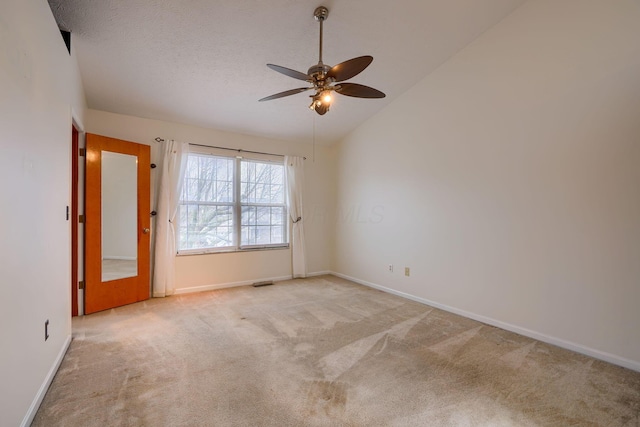 carpeted spare room with ceiling fan, vaulted ceiling, and a textured ceiling