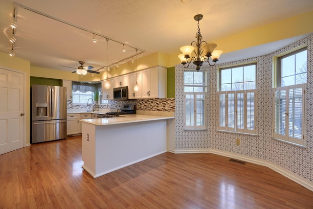 kitchen with white cabinetry, hanging light fixtures, stainless steel appliances, a healthy amount of sunlight, and kitchen peninsula