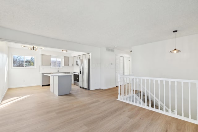 unfurnished room with a notable chandelier, a textured ceiling, and light wood-type flooring