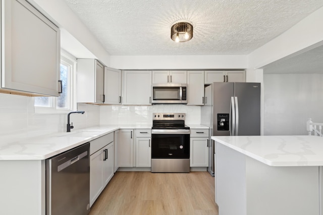 kitchen featuring stainless steel appliances, tasteful backsplash, gray cabinets, and sink