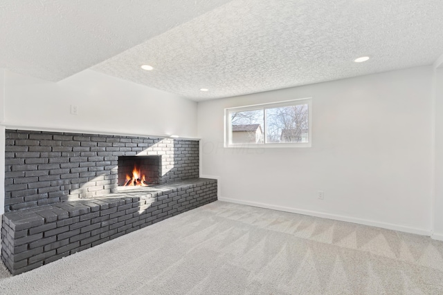 unfurnished living room featuring light colored carpet, a brick fireplace, and a textured ceiling