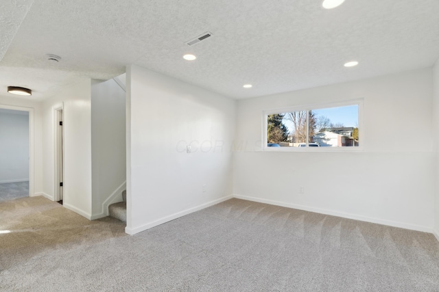 carpeted empty room featuring a textured ceiling