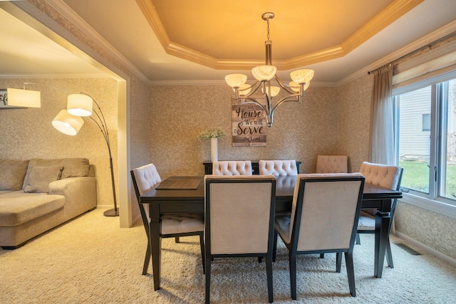 carpeted dining space featuring a tray ceiling, ornamental molding, and a chandelier