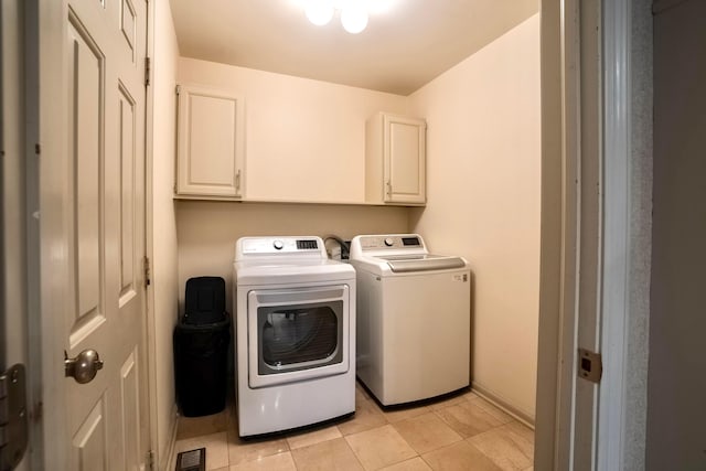 laundry area featuring cabinets, light tile patterned floors, and washing machine and clothes dryer